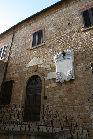 Lapide commemorativa sul muro di un antico edificio in pietra, con dettagli architettonici caratteristici.