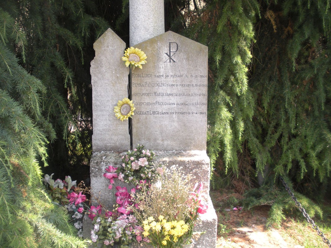 Lapide commemorativa ai caduti civili di Bosnasco, adornata con fiori, tra alberi verdi.