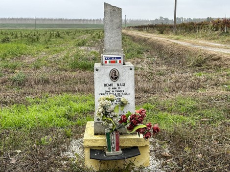 Cippo commemorativo dedicato a Remo Nasi, situato in una campagna tranquilla.