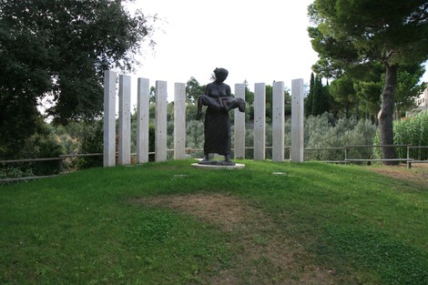Monumento del Parco della Memoria, con statua centrale circondata da pannelli commemorativi in un'area verde.