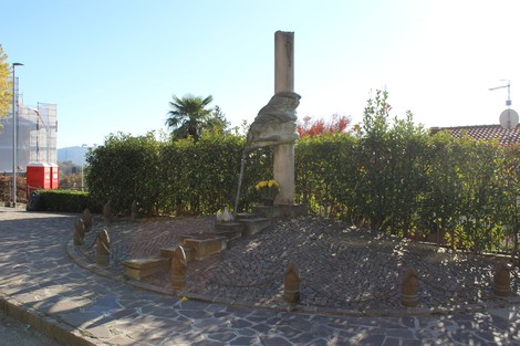 Monumento alla Resistenza, una scultura circondata da un giardino ordinato e illuminata dalla luce del sole.