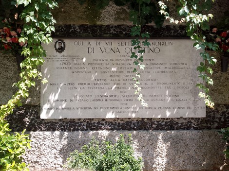 Lapide commemorativa a Di Vona, incastonata in una parete di pietra e circondata da vegetazione.