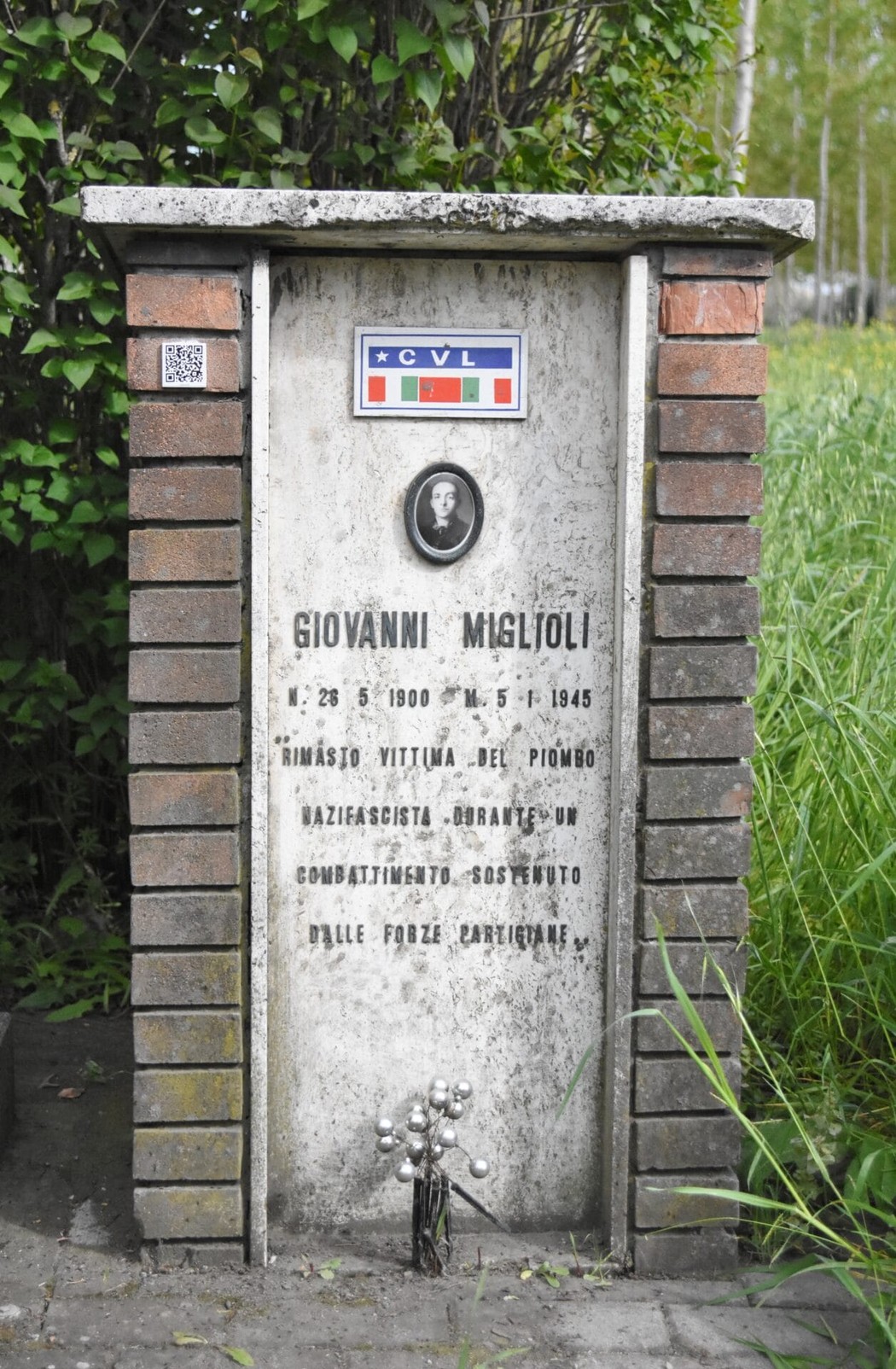 Cippo commemorativo dedicato a Giovanni Miglioli, eroe della Resistenza, con un design sobrio e significativi dettagli.