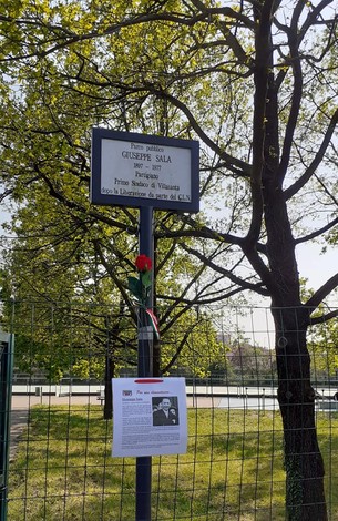 Targa commemorativa dedicata a Giuseppe Sala, situata in un'area verde, con fiori e informazioni storiche.