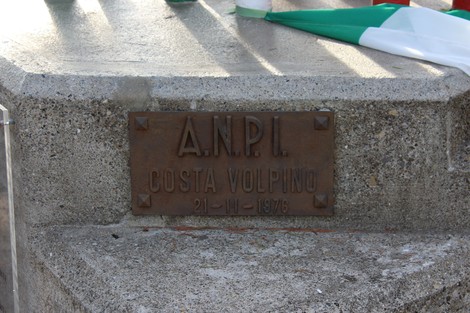 Monumento ai caduti partigiani con iscrizione commemorativa in metallo su base di cemento.
