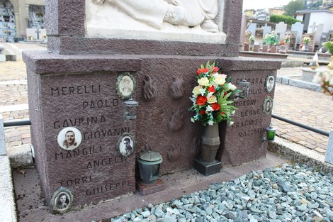 Monumento ai Caduti partigiani, con nomi incisi e fiori commemorativi, situato in un cimitero.