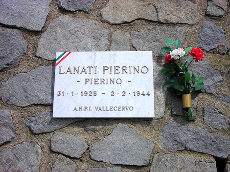 Lapide commemorativa di Pierino Lanati, con fiori e stendardi tricolori, in memoria della sua vita.