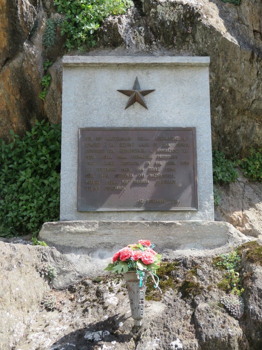 Monumento ai caduti del rifugio GEAT e alla Brigata Carli, con decorazioni floreali e stella rossa.
