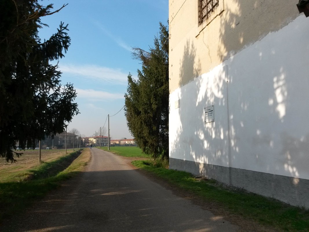 Lapide commemorativa dedicata a Ferrari, visibile lungo una strada di campagna.
