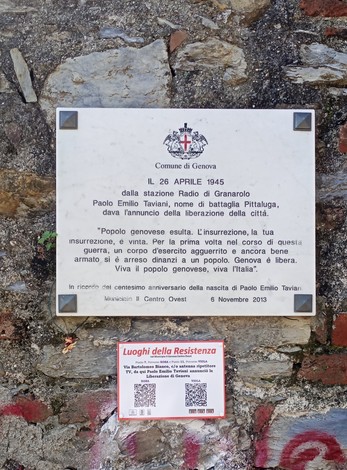 Lapide commemorativa che celebra l'annuncio della Liberazione a Genova, con riferimento storico e simbolico.