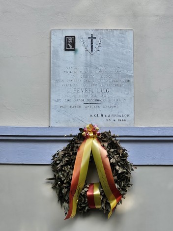 Lapide commemorativa a Peveri, con corona di alloro e nastri colorati, in segno di rispetto e memoria.