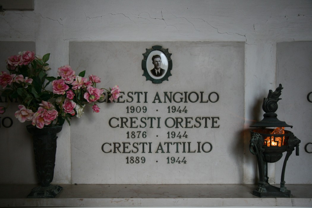 Sepolcro delle vittime dell'eccidio di Pratale, con lapidi e ornamenti floreali, in un'atmosfera di rispetto e memoria.