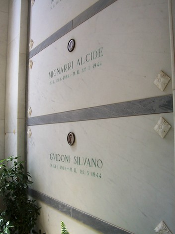 Interno della Cappella dei Caduti di Istia d'Ombrone, mostrando loculi marmorei in un'atmosfera di commemorazione.