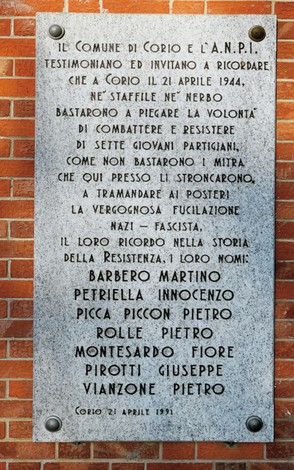 Lapide in marmo fissata su una parete, con iscrizione e sette nomi di partigiani fucilati.