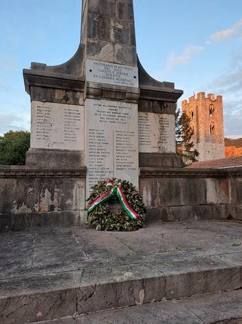Monumento commemorativo ai caduti di Vecchiano con una corona d'alloro e un suggestivo sfondo storico.