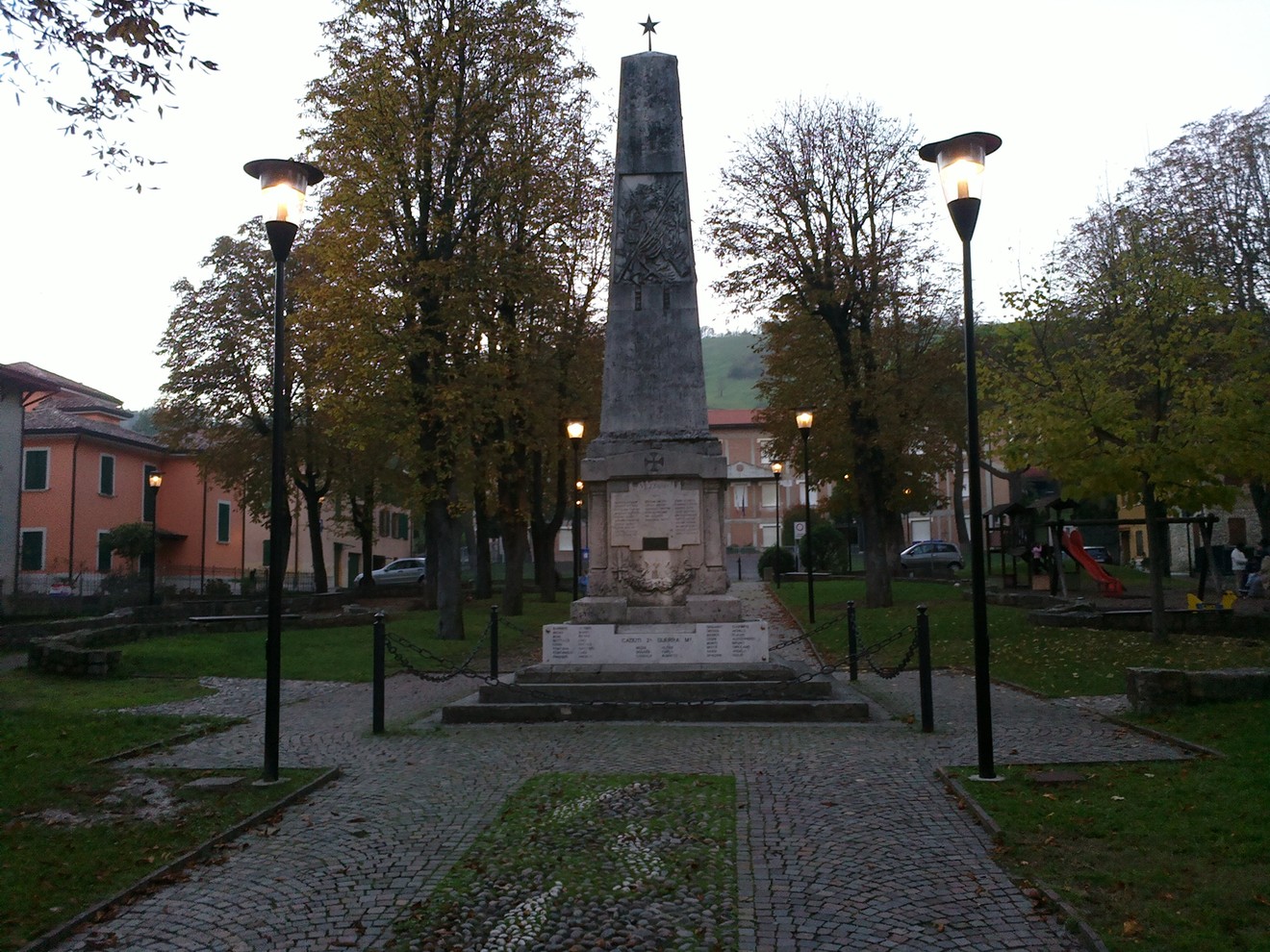 Monumento ai Caduti di Vezzano, dedicato ai sacrifici dei soldati locali, circondato da un verde parco pubblico.