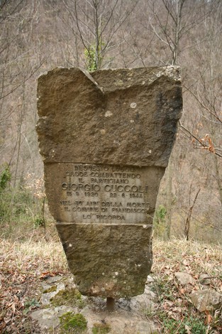 Monumento in pietra dedicato a Giorgio Cuccoli, situato in un ambiente naturale.