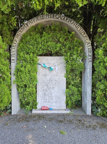 Monumento alle Vittime dell'eccidio dell'Aeroporto di Forlì, circondato da vegetazione e decorazioni.