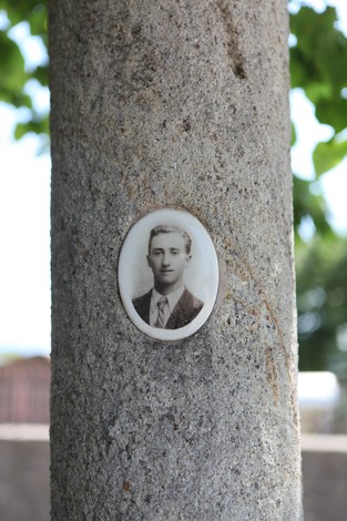 Monumento commemorativo con fotografia storica incastonata in una colonna di pietra.