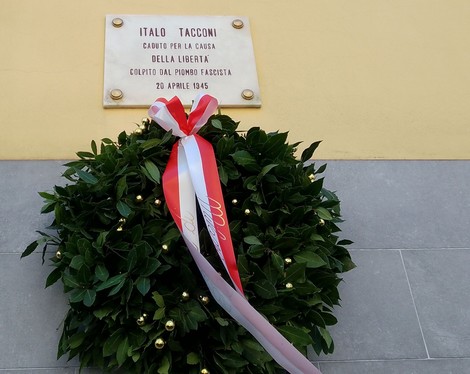 Lapide commemorativa di Italo Tacconi, con una corona di fiori e nastri, dedicata ai caduti per la libertà.