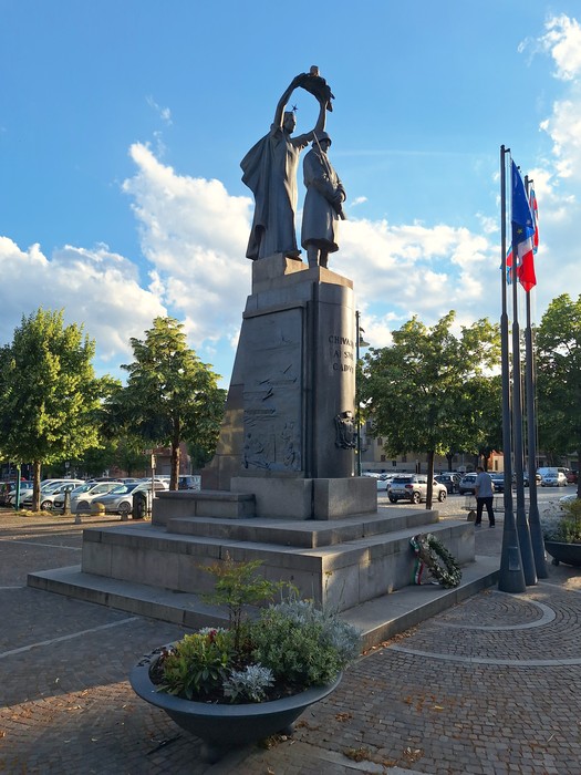 Bassorilievo commemorativo che celebra la lotta partigiana, situato nel monumento ai caduti, con figure simboliche e vegetazione circostante.