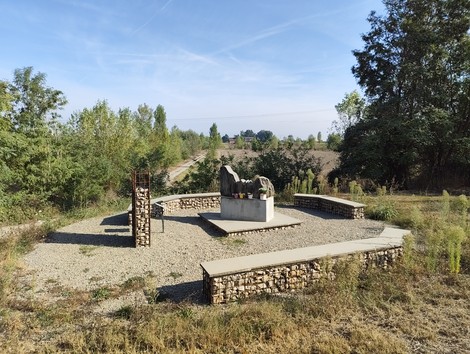 Il Monumento ai Martiri del Panaro si erge in un'area verde circondata da alberi e sentieri.