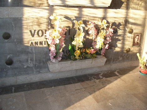 Cappella dei partigiani con fiori ornamentali e ombre evocative. Luogo di memoria storica e rispetto.