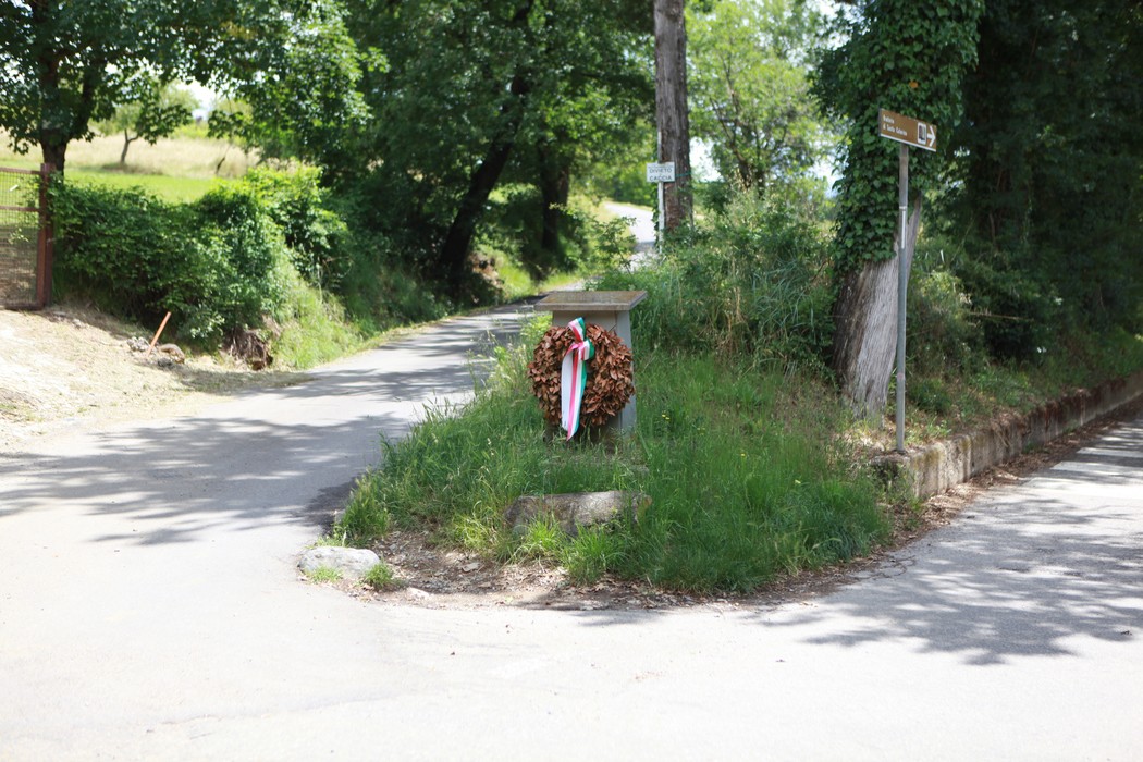 Cippo di Villa La Selva, monumento immerso nel verde, segna l'incrocio di due strade in un paesaggio naturale.