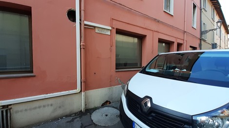 Lapide commemorativa dedicata a Beltrandi su un muro di un edificio, con un veicolo parcheggiato vicino.