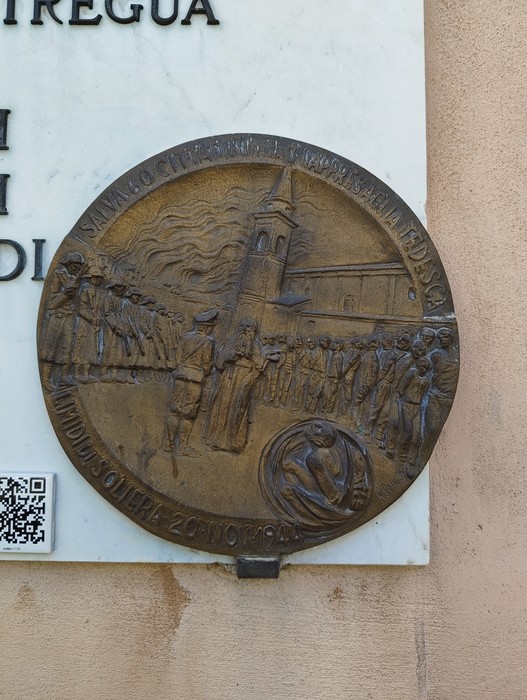 Lapide commemorativa per gli ostaggi liberati, con rilievo di figure e architettura storica.