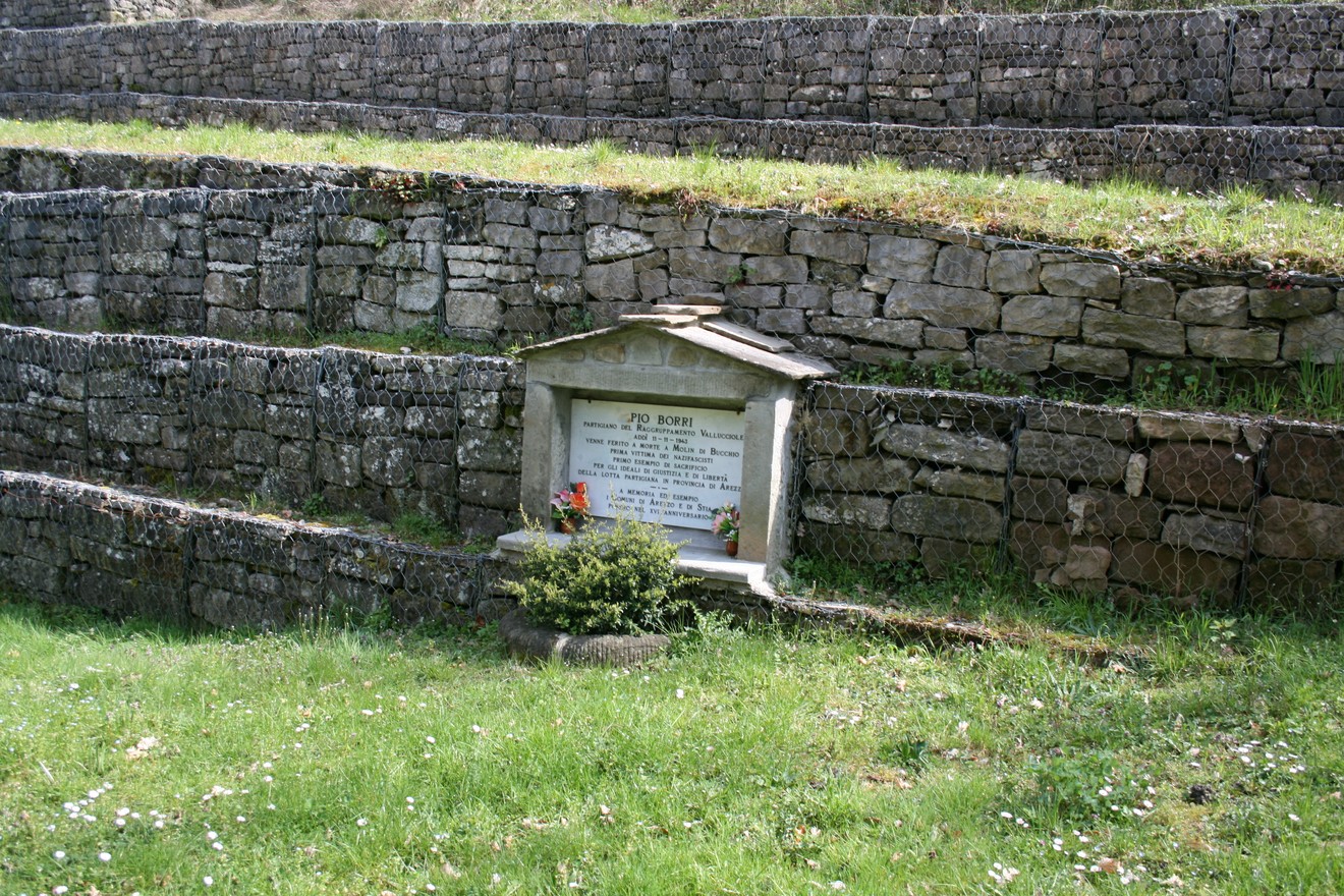 Lapide commemorativa a Borri, immersa nel verde, circondata da muri in pietra.