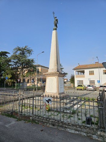 Monumento ai Caduti di Saletta, obelisco con figura allegorica, circondato da una recinzione, in un contesto urbano.