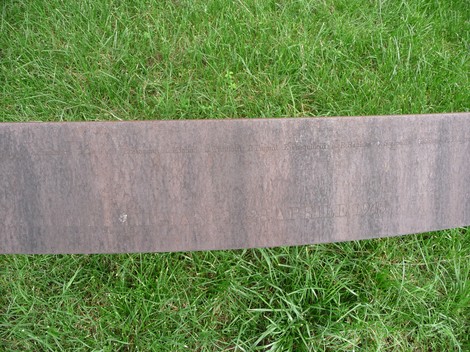 Monumento dedicato ai caduti partigiani, realizzato in un design semplice su un fondale di erba verde.
