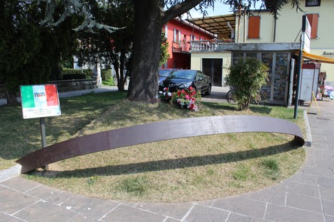 Monumento ai caduti partigiani, caratterizzato da una struttura in metallo, immerso in un verde parco urbano.