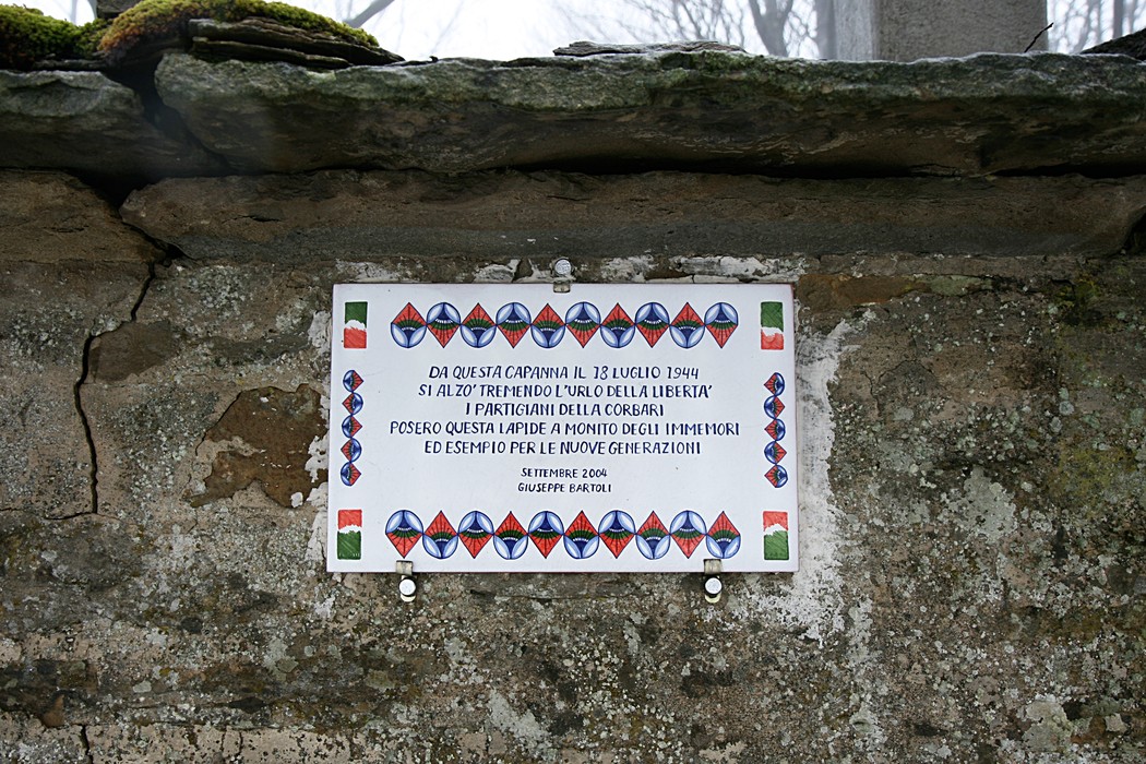 Lapide commemorativa in ricordo dei partigiani, installata su un'antica capanna.