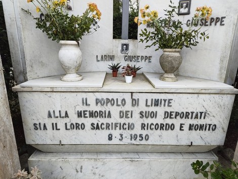 Monumento dedicato ai deportati, con iscrizioni commemorative e fiori sulle lapidi. Luogo di memoria e rispetto.