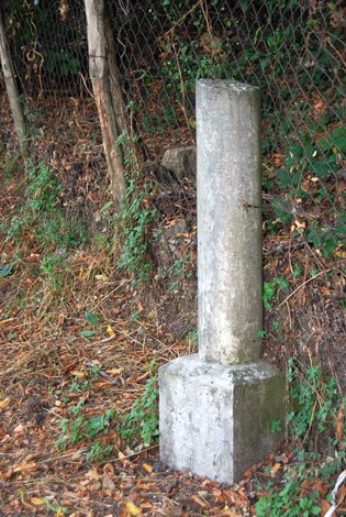 Cippo a tronconi in calcestruzzo, situato in un'area naturale con vegetazione circostante.