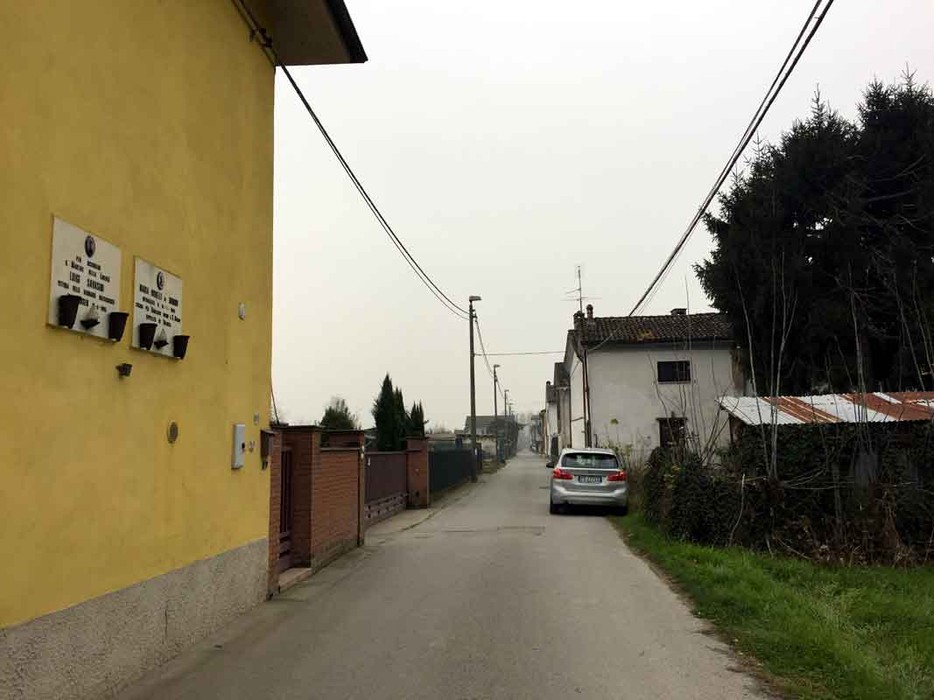 Veduta di una strada con case e lapidi, che rappresentano la località di Orbelli e Savasini.
