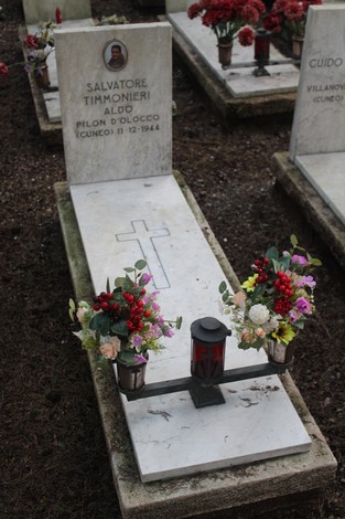 Tombe di caduti per la Libertà, con fiori e lanterna commemorativa in un cimitero.