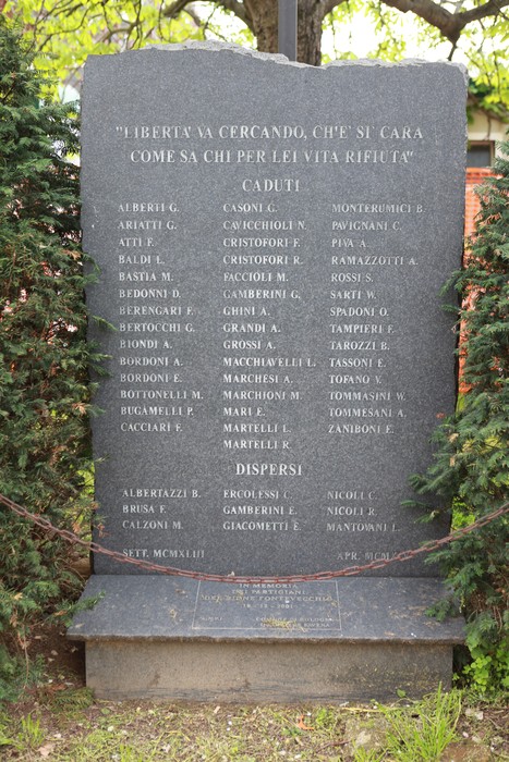 Cippo commemorativo dedicato ai partigiani del Pontevecchio, circondato da vegetazione, ricorda valorosi caduti.