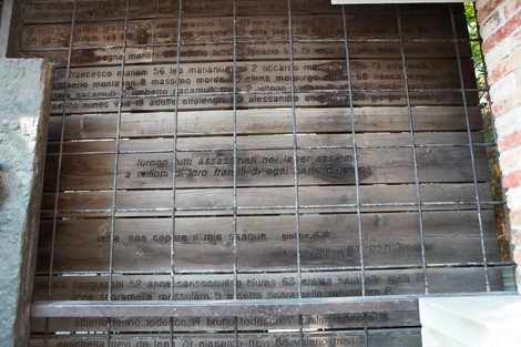 Immagine di una superficie di legno con iscrizioni che ricordano eventi o persone legate a "L'ultimo treno".