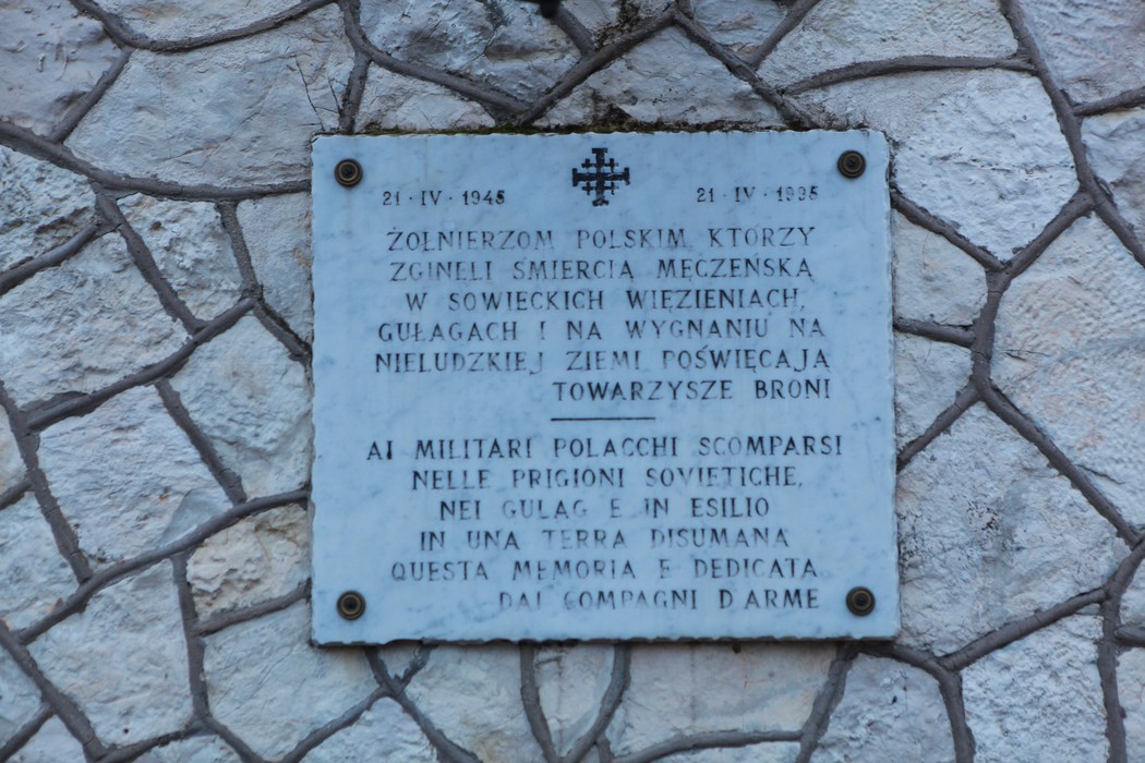 Cimitero di guerra polacco, con monumento commemorativo su una parete di pietra. Atmosfera di ricordo e rispetto.