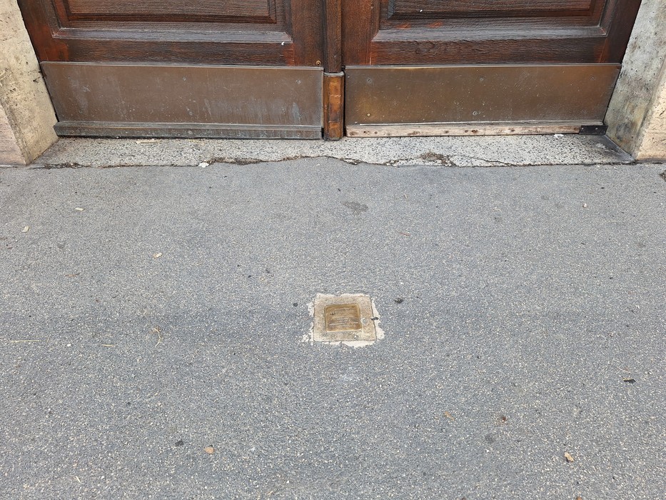 Pietra d'inciampo a Gatti incastonata nel pavimento vicino a una porta, simbolo della memoria storica.