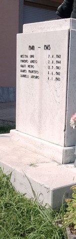 Monumento ai caduti con iscrizioni in memoria dei soldati, circondato da erba verde.