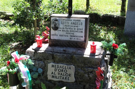 Monumento commemorativo a Gotti Angelo, partigiano, con scritte e decorazioni di omaggio in un contesto naturale.
