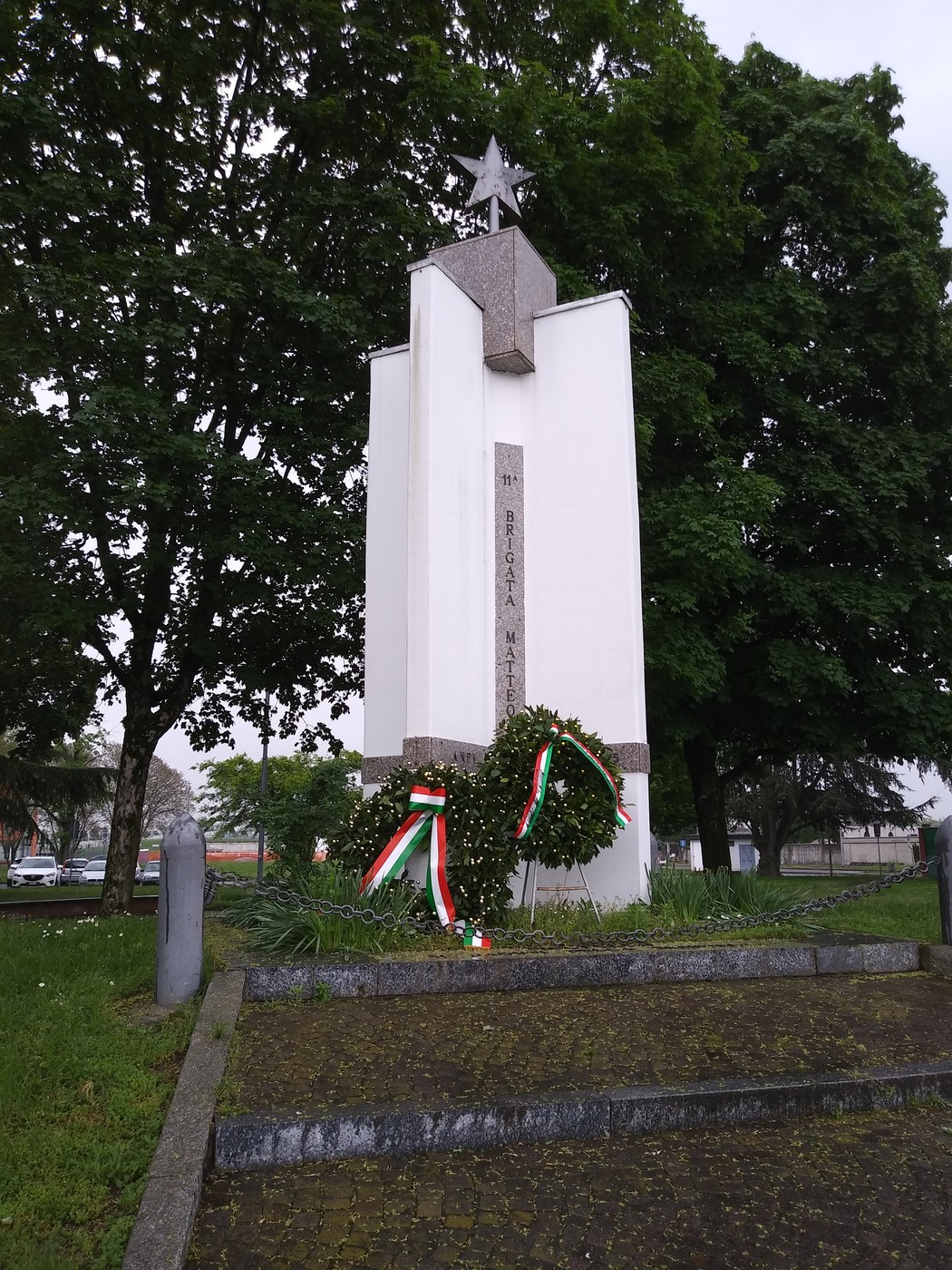 Monumento ai caduti della Resistenza, con decorazioni tricolori e una grande stella, immerso nel verde.