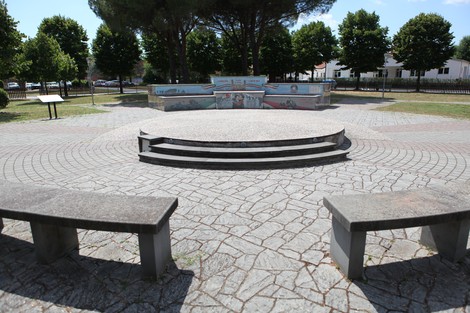 Murali colorati nel parco della Liberazione, con panchine in un'area centrale circondata da alberi.