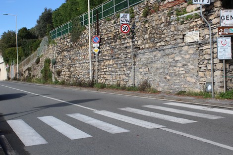 Lapide a Zanchetta su una parete di pietra vicino alla strada con segnaletica stradale e strisce pedonali.