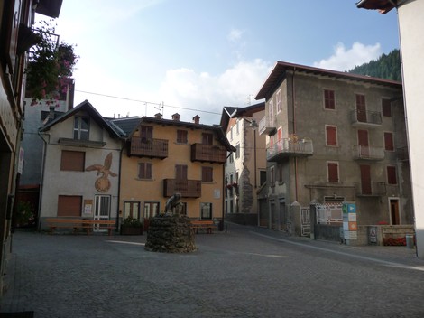 Veduta di una piazza caratteristica con edifici storici e una lapide commemorativa sui Caduti per la Libertà.