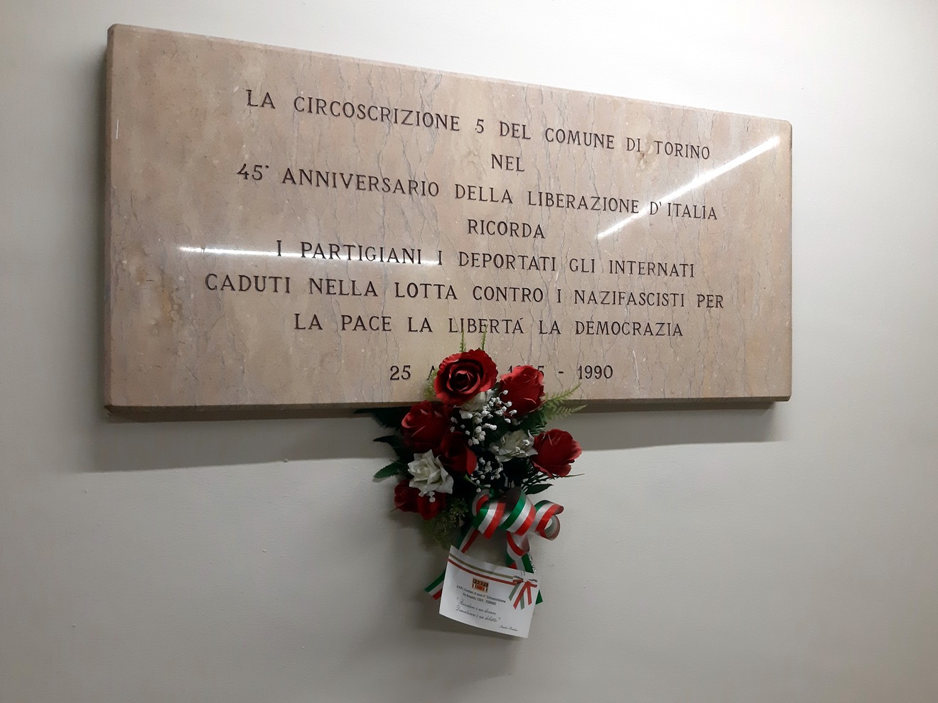 Lapide commemorativa per il 45° anniversario della Liberazione, con omaggio floreale.